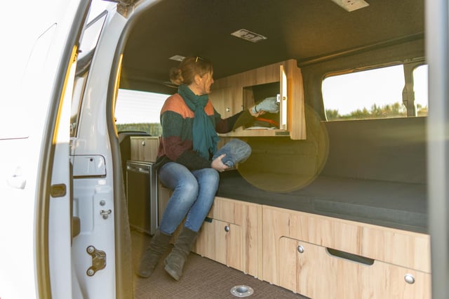 Intérieur de l'Aventourer Origin X2 avec meuble bois et porte latérale ouverte