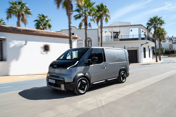Kia PV5 Cargo tôlé gris acier en circulation, vue 3/4 avant — illustration de la gamme