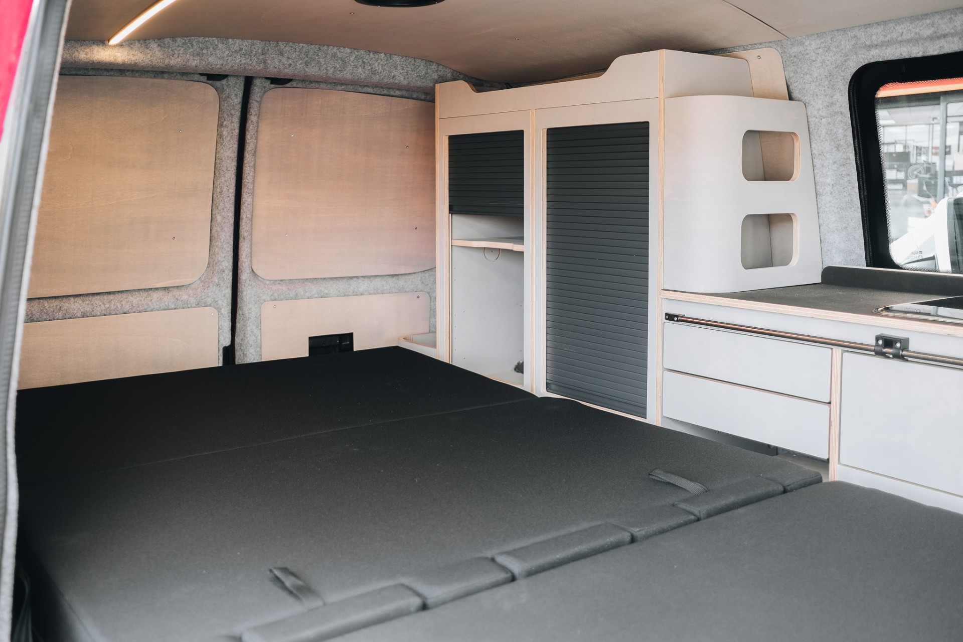 Volkswagen T5 rouge aménagé — module cuisine