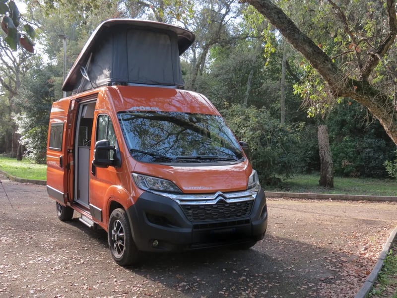 Fourgon orange avec toit relevable Sky-Up ouvert, porte latérale ouverte