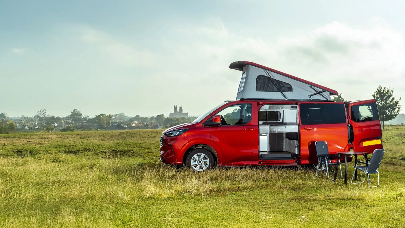 Van aménagé avec toit relevable SKYVAN technologie Austops ouvert, garé dans un pré