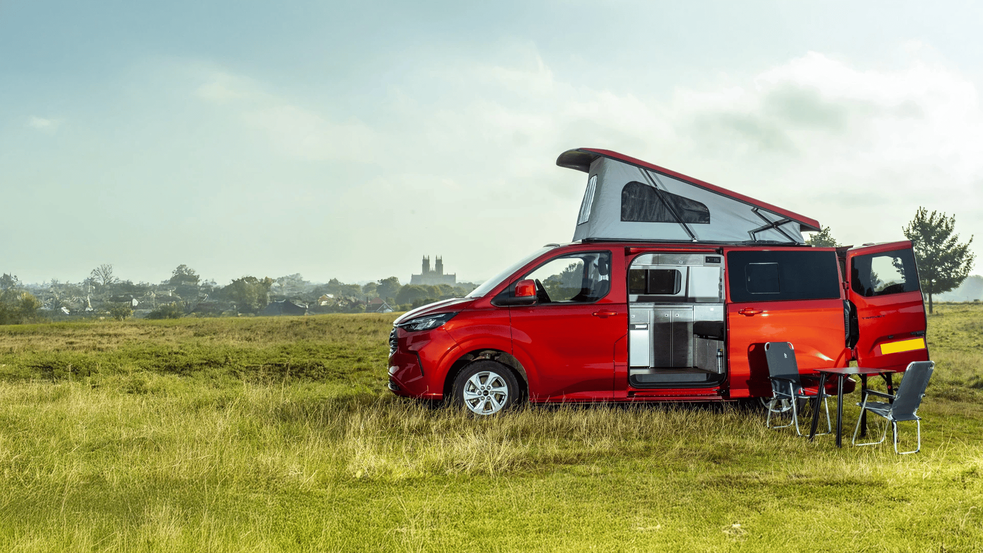 Van aménagé avec toit relevable SKYVAN technologie Austops ouvert, garé dans un pré